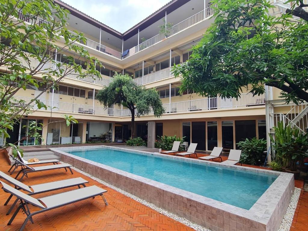 a pool in the courtyard of a building with lounge chairs at Feung Nakorn Balcony Rooms and Cafe in Bangkok