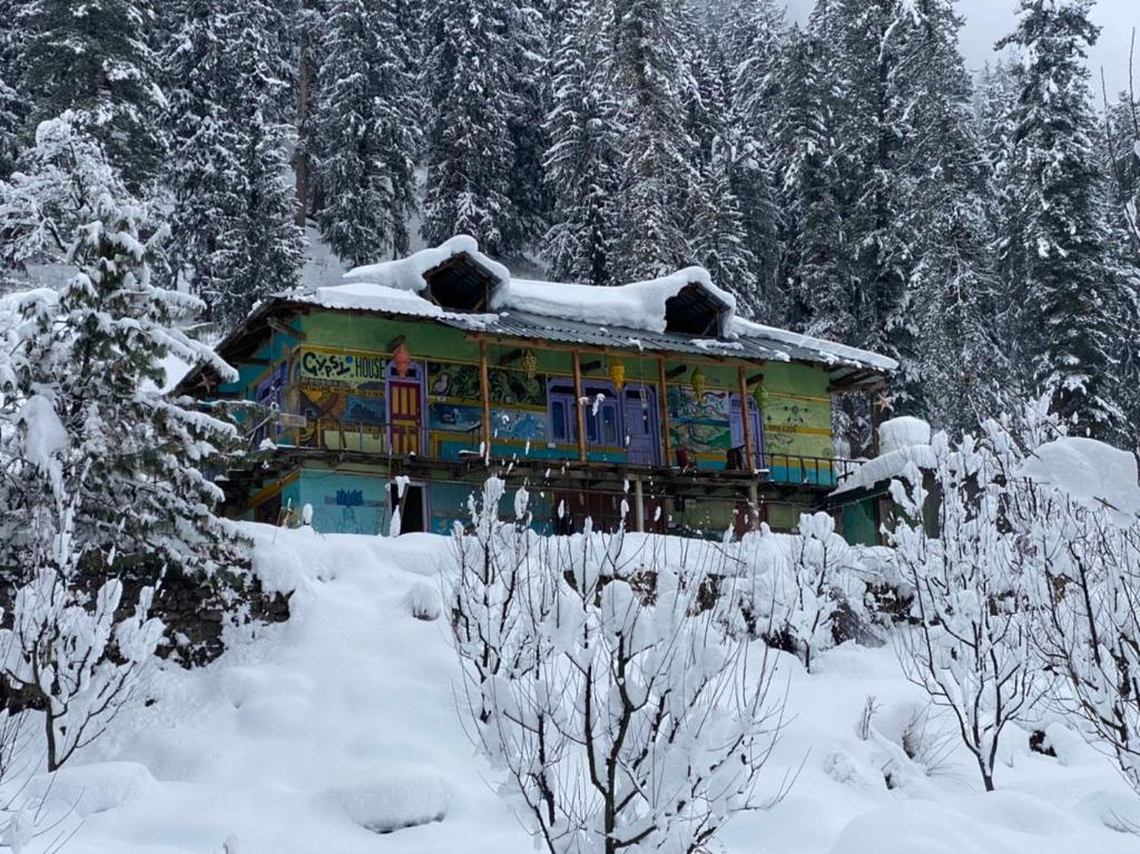 una casa cubierta de nieve frente a los árboles en Gypsy House, en Kalgha