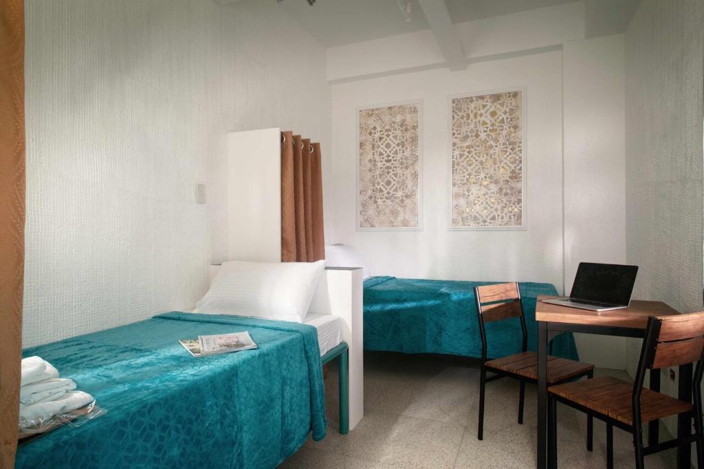 a room with two beds and a table with a laptop at 1001 Nights Boutique Inn in Cagayan de Oro