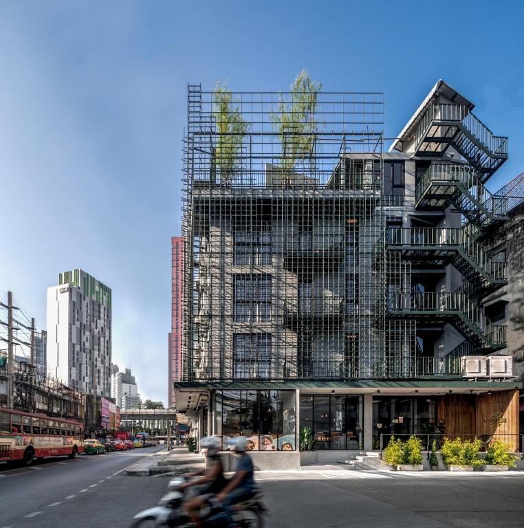 two people riding a motorcycle in front of a building at Goose Living Bangkok BTS Phra Khanong in Bangkok