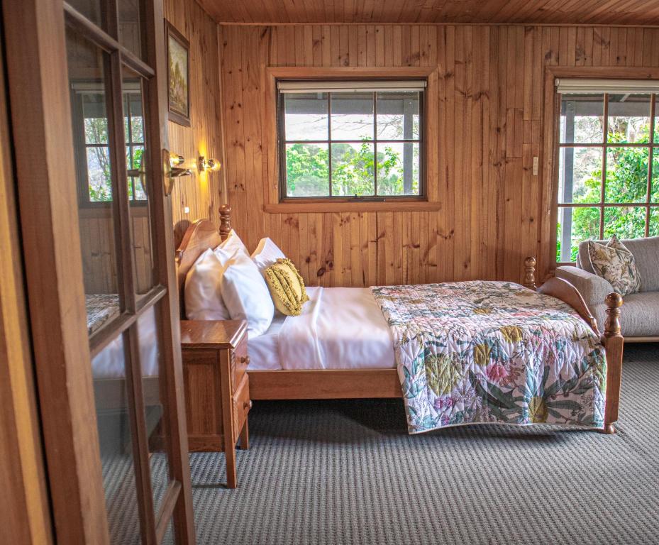 a bedroom with a bed and two windows at Gaol House Cottages in Bicheno