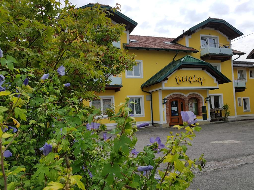 ein gelbes Gebäude mit lila Blumen davor in der Unterkunft Pension Baumgartner-Berghof in Obernberg am Inn