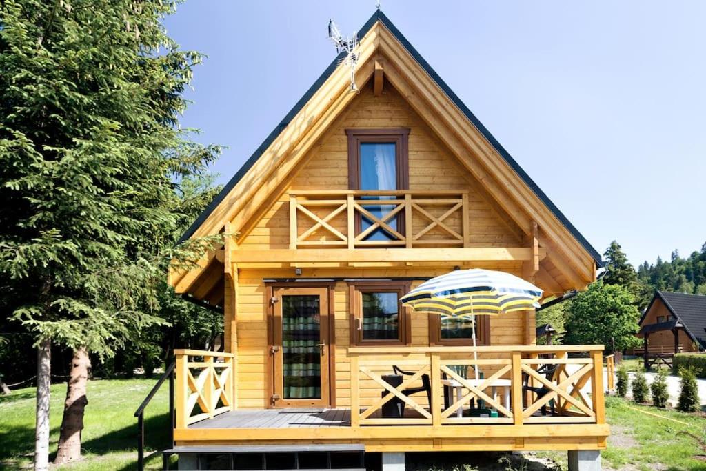 a log cabin with an umbrella on the deck at DOMKI JANOSIK - Janosik Premium in Łopuszna