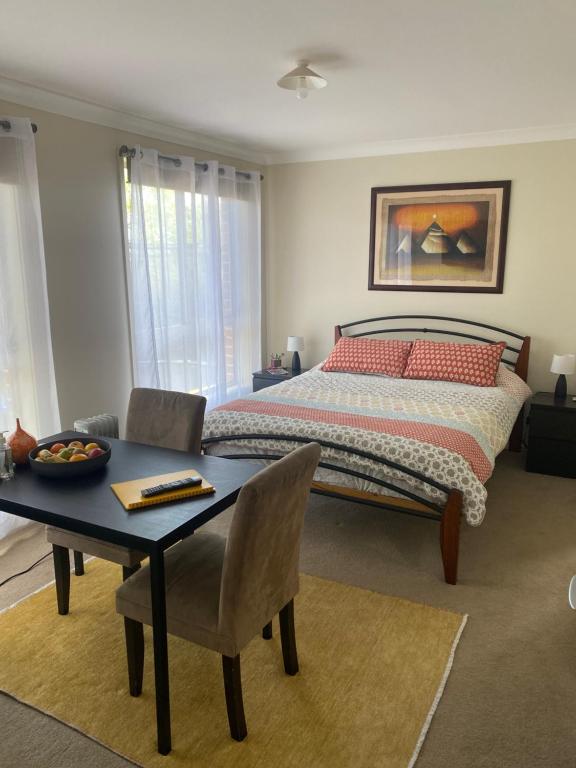 a bedroom with a bed and a table and chairs at Private room with ensuite and parking close to Wollongong CBD in Wollongong