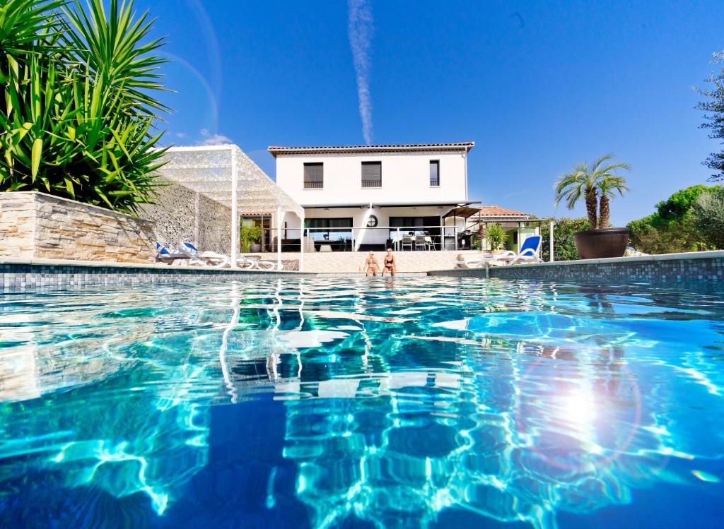 une piscine avec une maison en arrière-plan dans l'établissement Villa Quietude, à Bagnols-en-Forêt