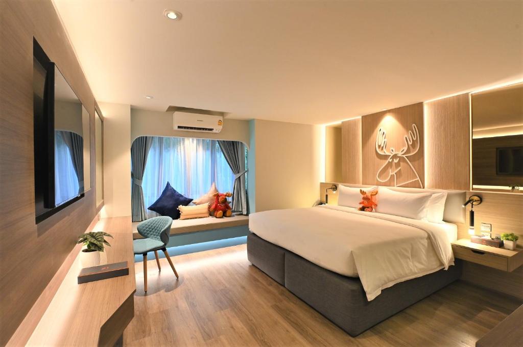 ein Schlafzimmer mit einem Bett und einem Fenster mit einem Zimmer mit einer Antilope in der Unterkunft Moose Hotel Nimman in Chiang Mai