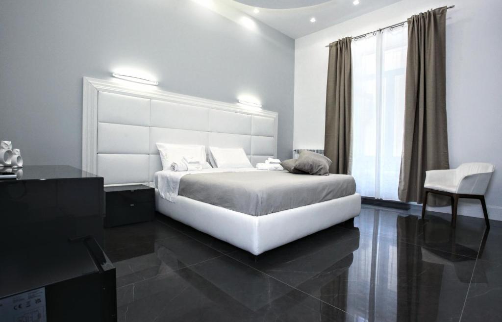 a white bedroom with a large bed and a chair at DUOMO LUXORY HOME in Naples