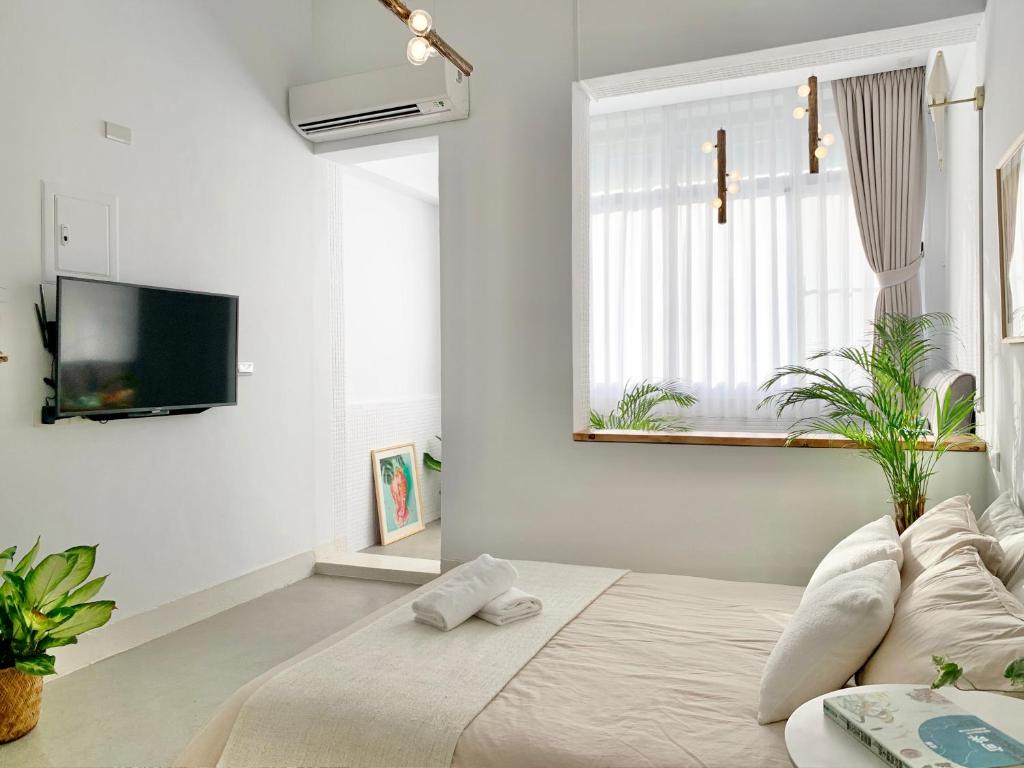 a white bedroom with a bed and a tv at 闆娘公寓 in Kaohsiung