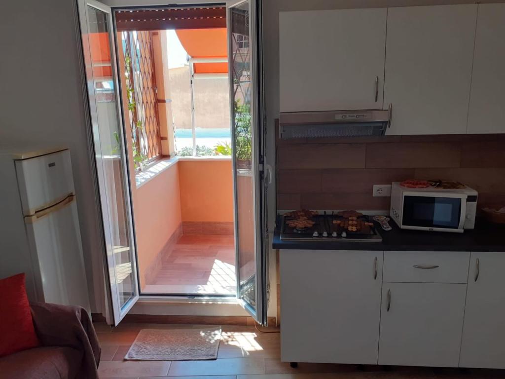 cocina con microondas y puerta a un balcón en Appartamentino Sogno di Circe en San Felice Circeo