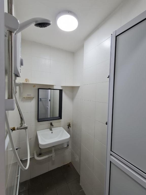 Un baño blanco con lavabo y espejo. en Homestay near to Georgetown, en Jelutong