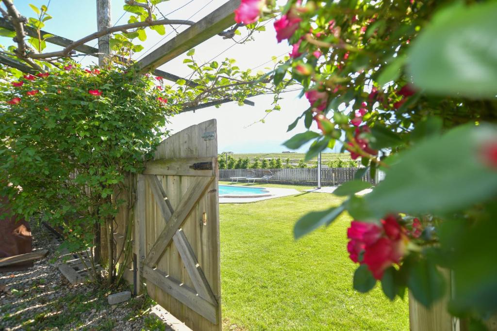 a wooden gate in a garden with pink roses at Valtlhof - Apt 2 in Cornaiano
