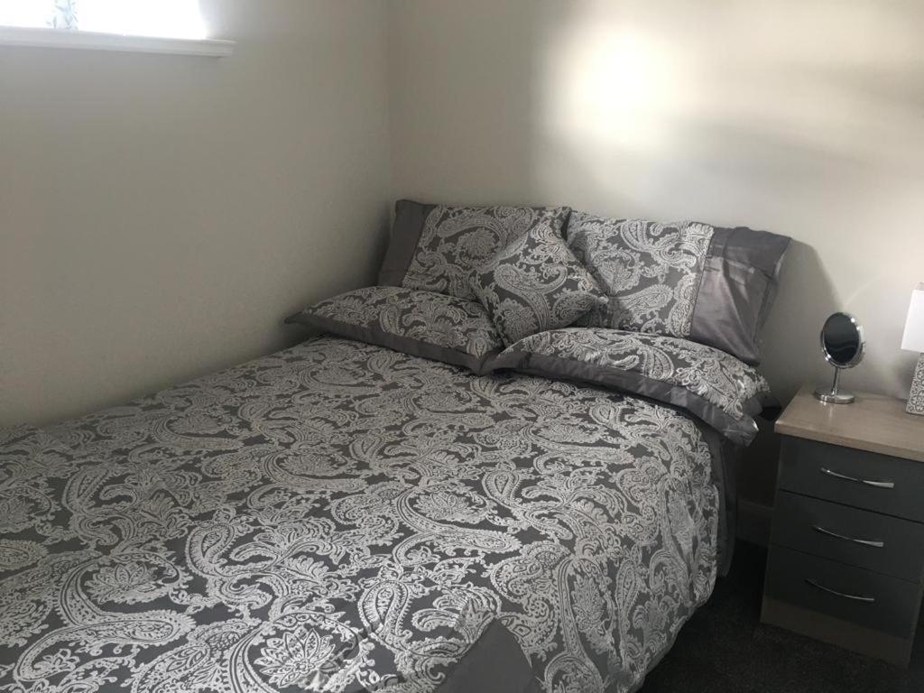 a bedroom with a bed with a gray blanket and pillows at Dympna's City Centre apartment, Armagh in Armagh