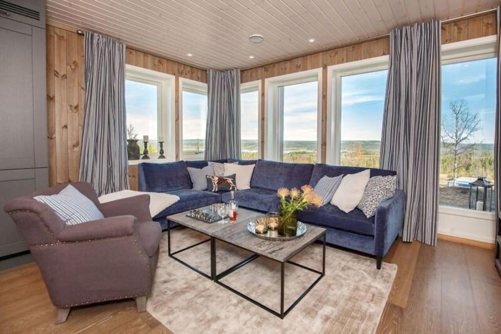 a living room with a blue couch and chairs and windows at Ny, flott fritidsleilighet i Bualie på Golsfjellet in Gol