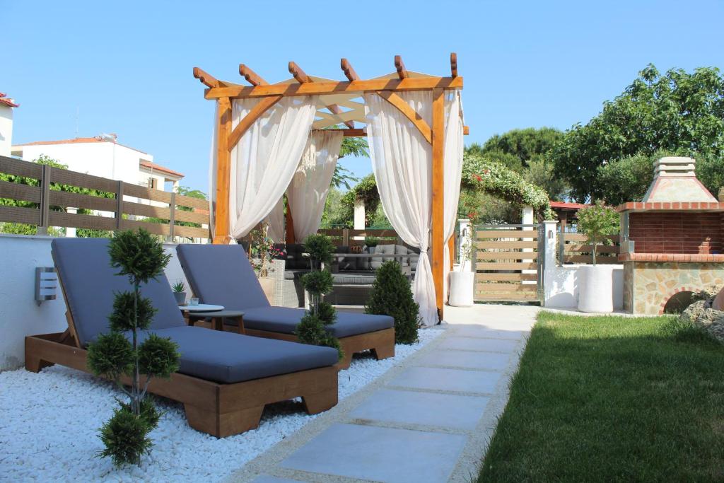 a garden with two chairs and a wooden pergola at Azure Bliss Suites in Nikiti