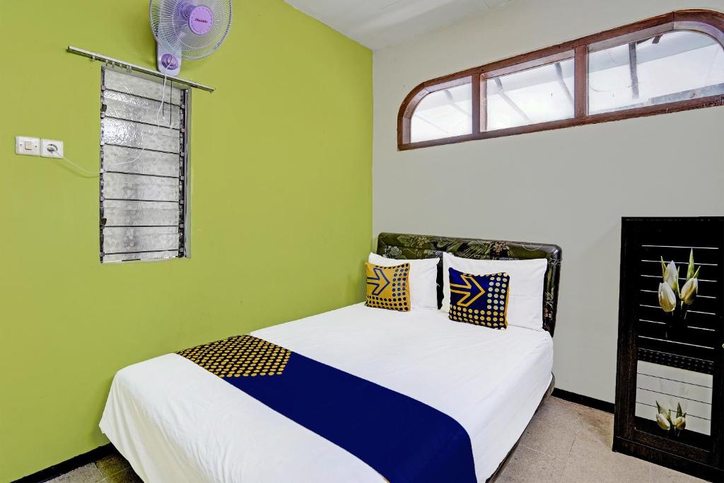 Mojokerto的住宿－SPOT ON 91716 Kost Yy Syariah，一间卧室设有一张带绿色墙壁和窗户的床。