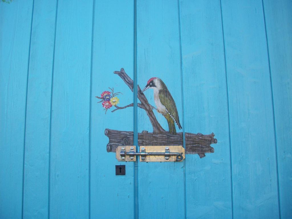 un dipinto di un uccello seduto su una mangiatoia per uccelli di Di Baut a Ovaro