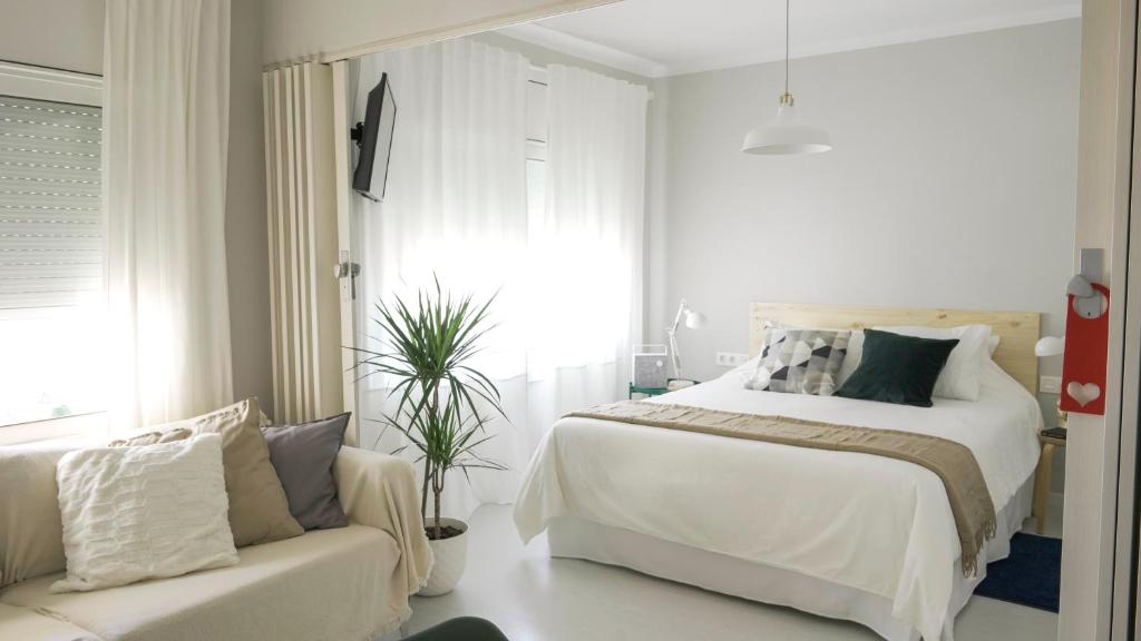 a white bedroom with a bed and a couch at At home, in the Heart of Sitges in Sitges