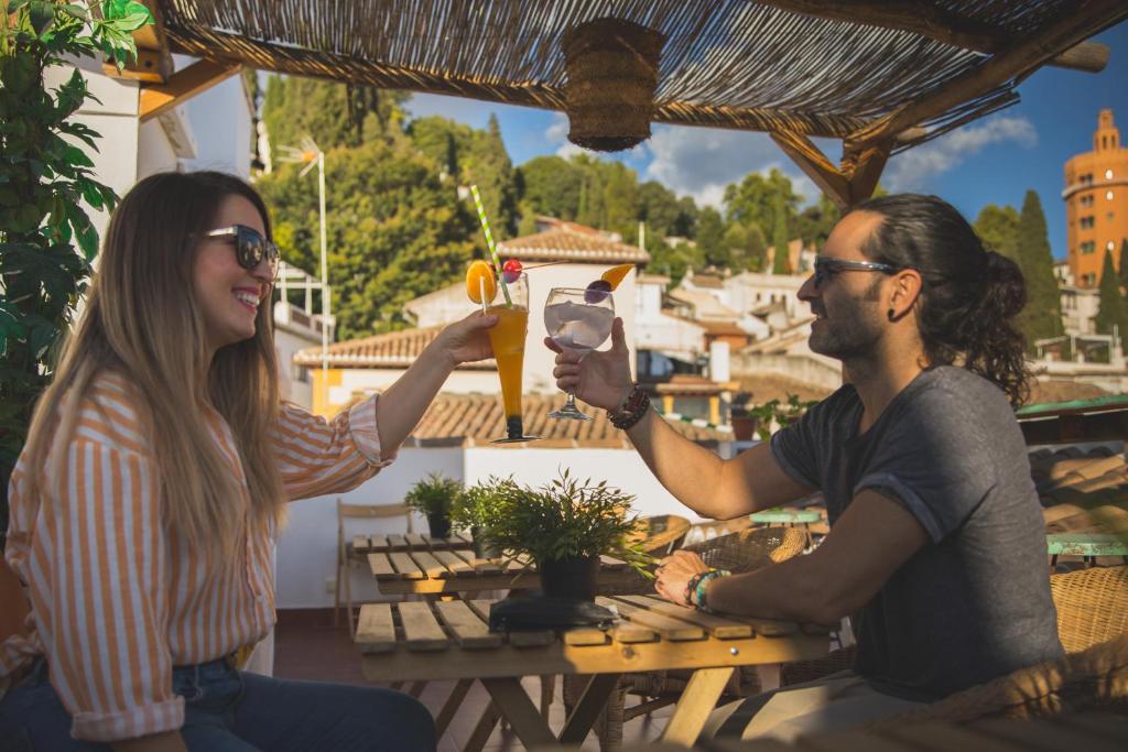 un hombre y una mujer sentados en una mesa bebiendo cerveza en Rooms Vita, en Granada