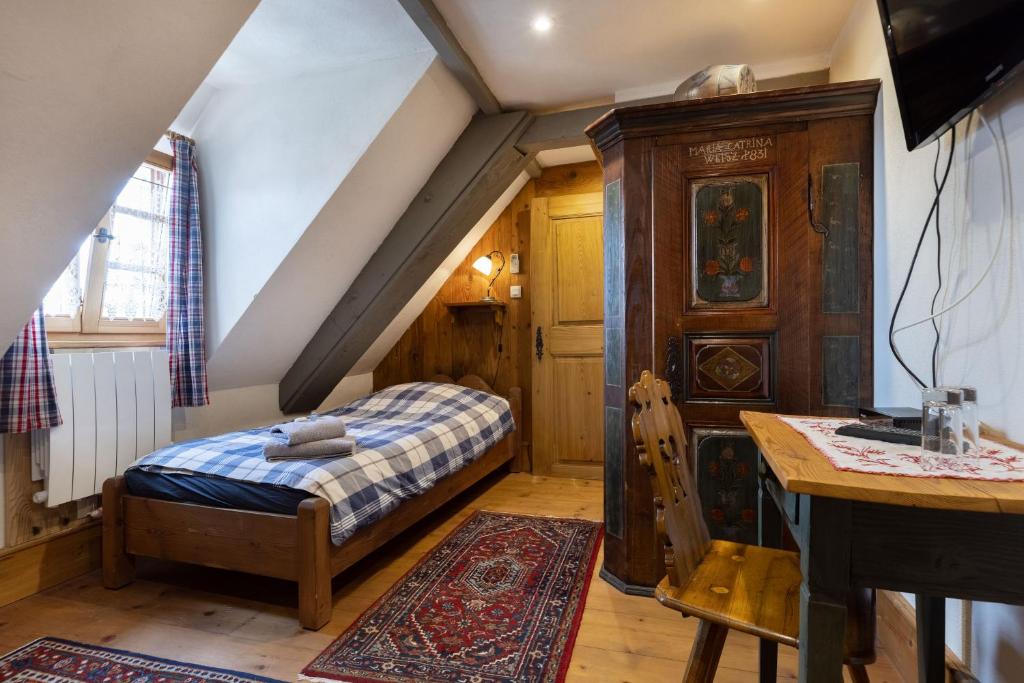 a small bedroom with a bed and a staircase at ANNO 1698 Gîtes et Chambres d'Hôtes in Beblenheim