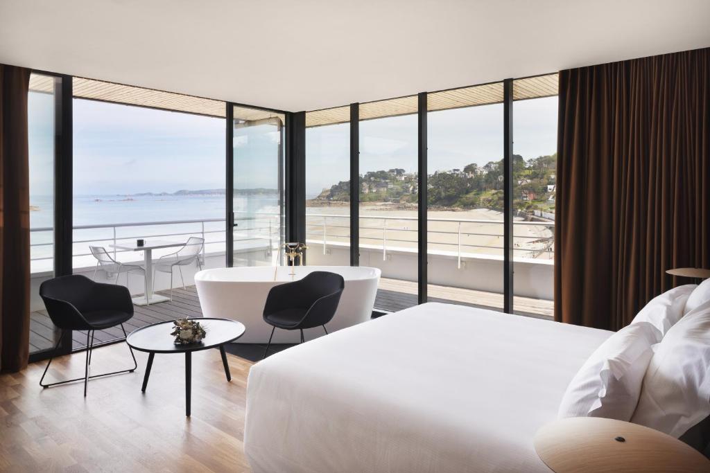 Habitación de hotel con cama, bañera y vistas a la playa. en Grand Hôtel Perros-Guirec en Perros-Guirec