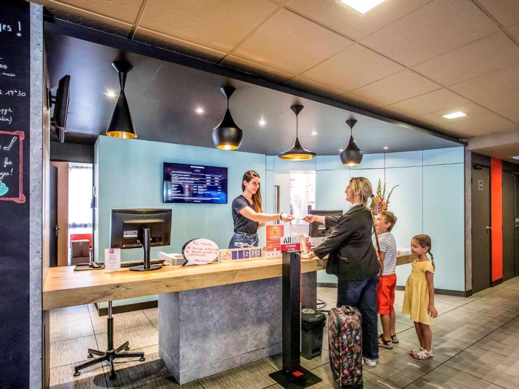 a woman and two children standing at a food counter at ibis Bourges Centre in Bourges