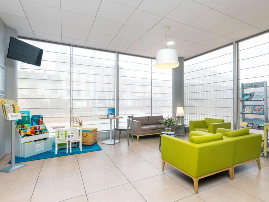 a waiting room with a green couch and a table at Aparthotel Adagio Access Nancy Centre in Nancy