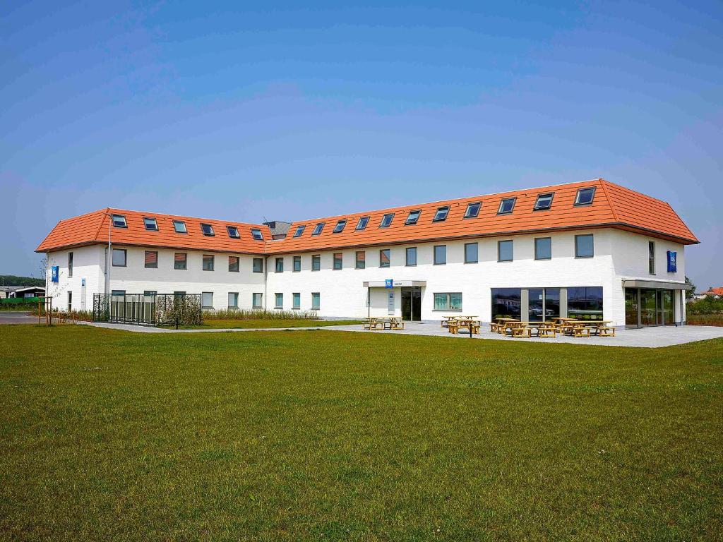 a large white building with an orange roof at ibis budget Oostende Airport in Ostend