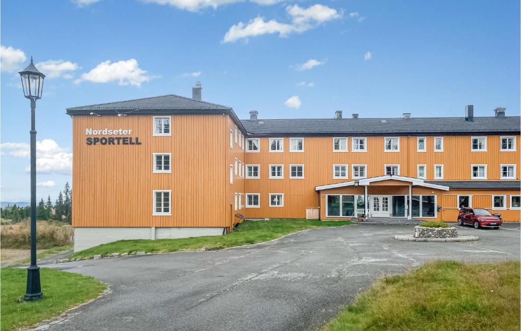 Amazing Apartment In Lillehammer With Sauna في ليلهامر: مبنى برتقالي وامامه موقف سيارات