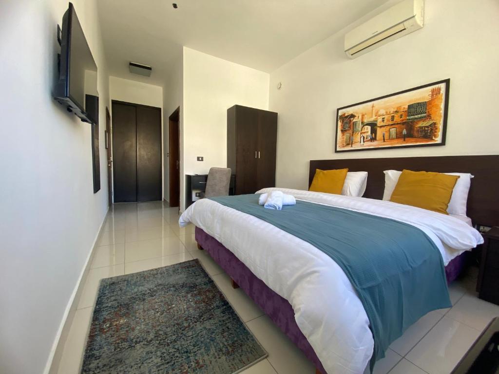 a bedroom with a large bed and a television at Lemon Tree Residence in Amman