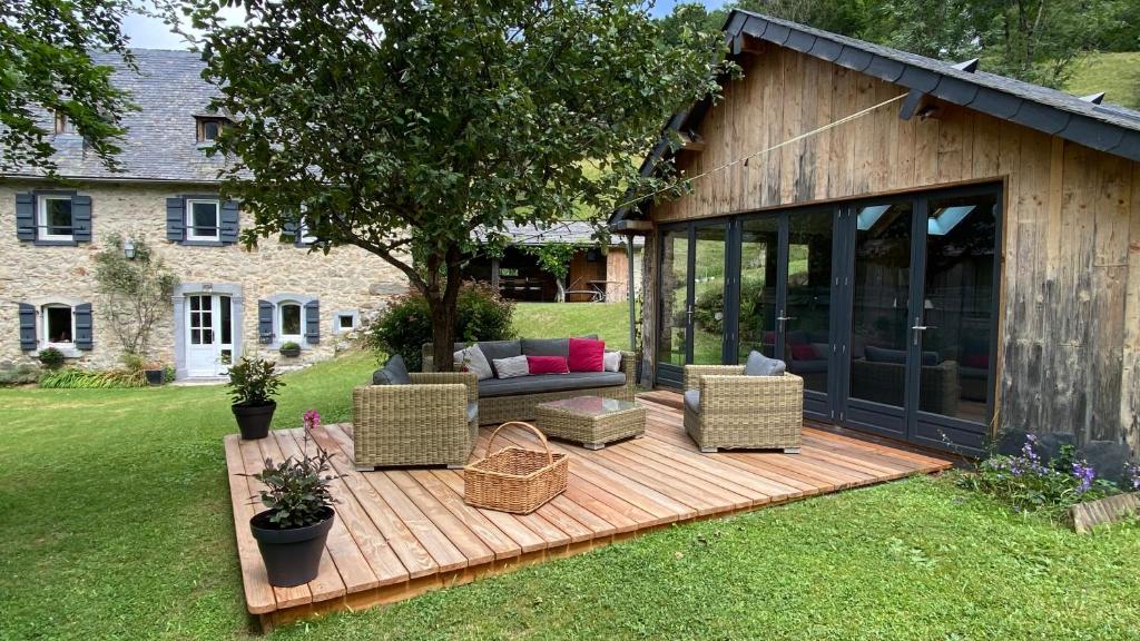a wooden deck with a couch and chairs in a yard at Le Domaine de Castille - maison pyrénéenne de charme - spa de nage in Arrens-Marsous