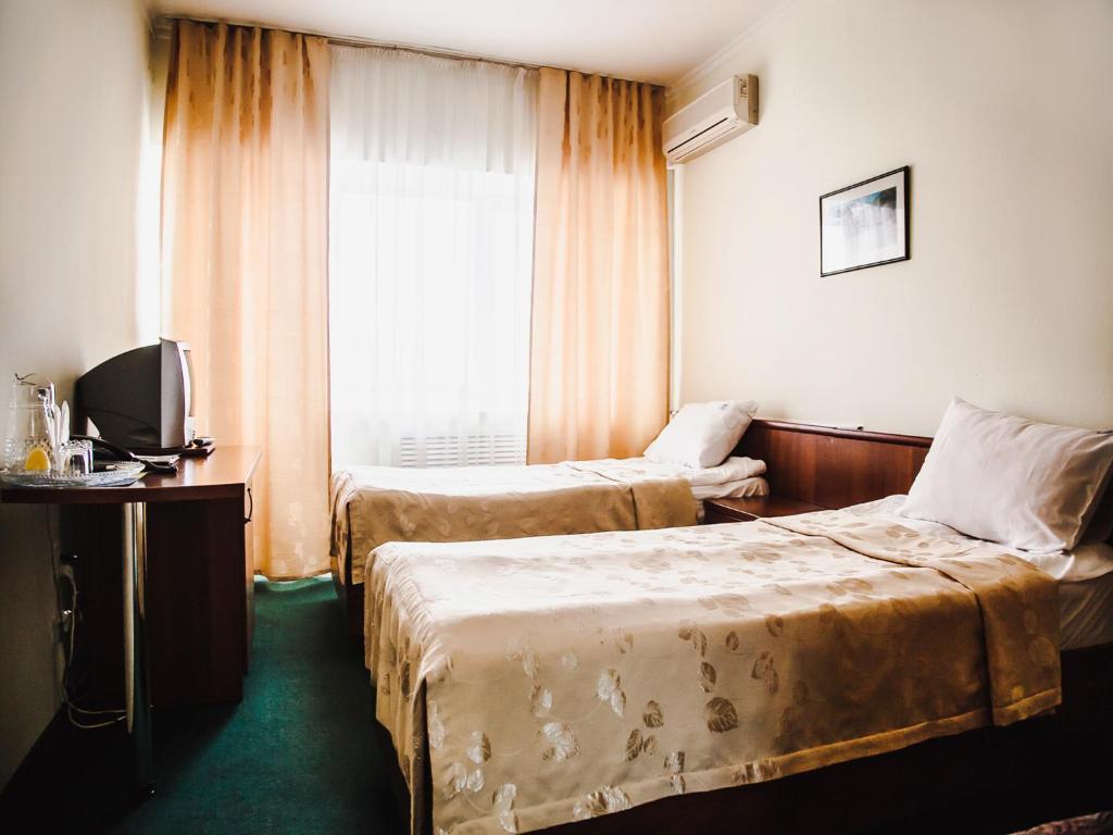 ピャチゴルスクにあるYuzhnaya Hotelのベッド2台と窓が備わるホテルルームです。