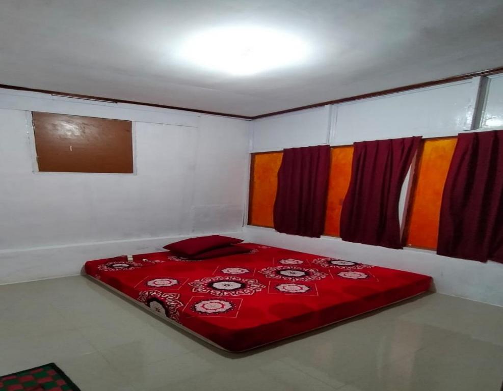 a red bed in a white room with colorful curtains at EXPRESS O 91702 Mandeh Homestay Syariah in Painan