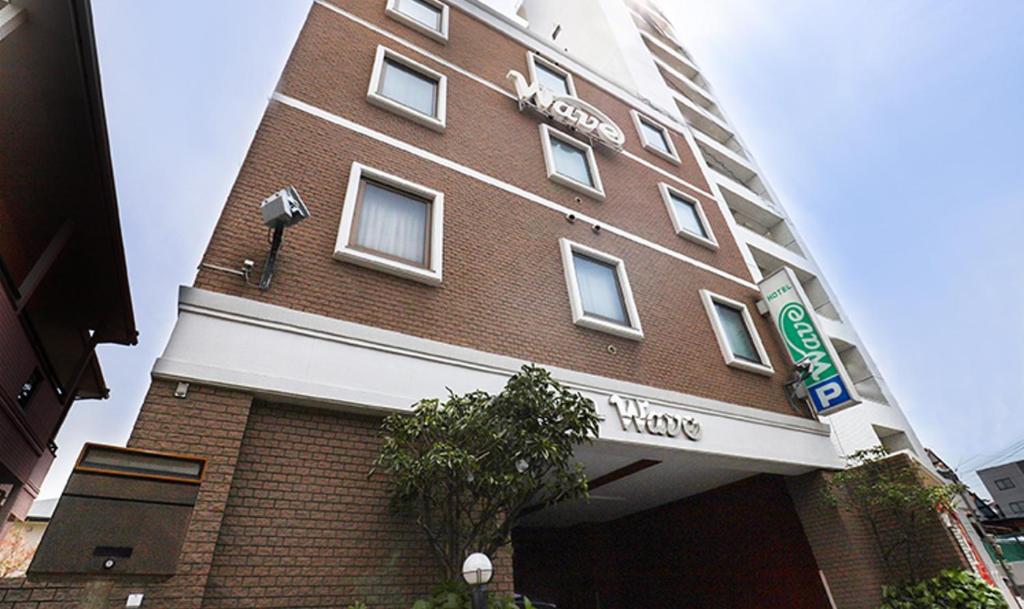 a tall brick building with a sign on it at Hotel Wave大人専用 in Hiroshima