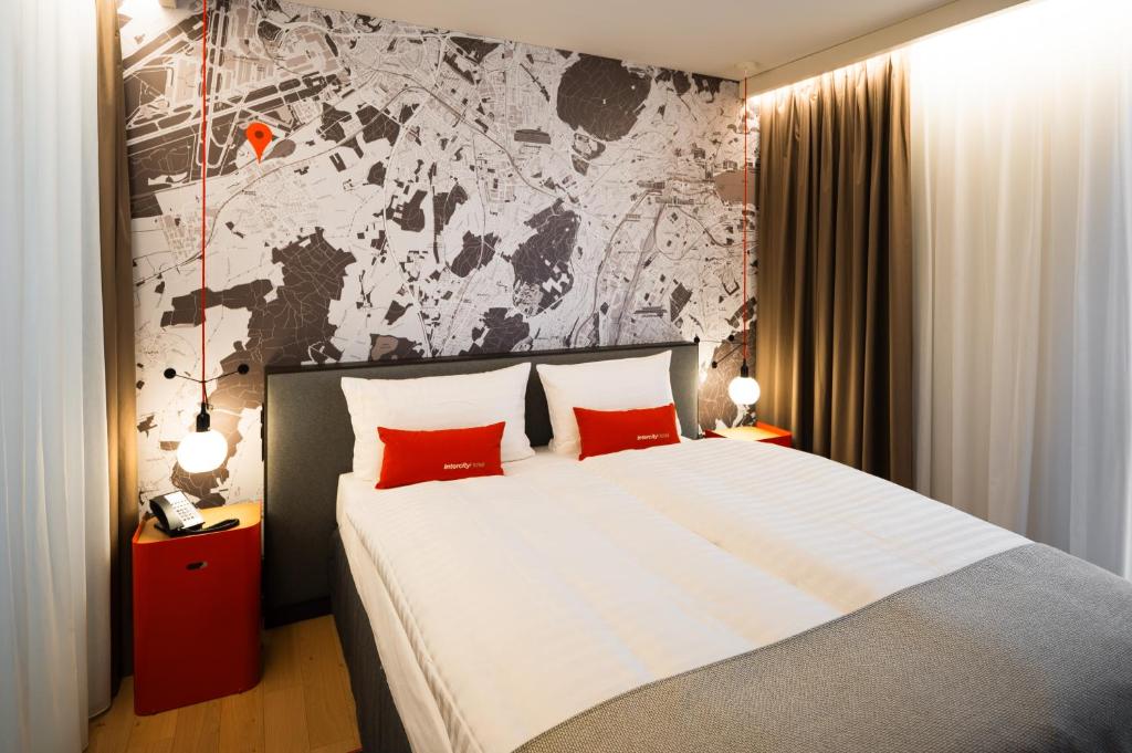 a bedroom with a large bed with two red pillows at IntercityHotel Geneva in Geneva