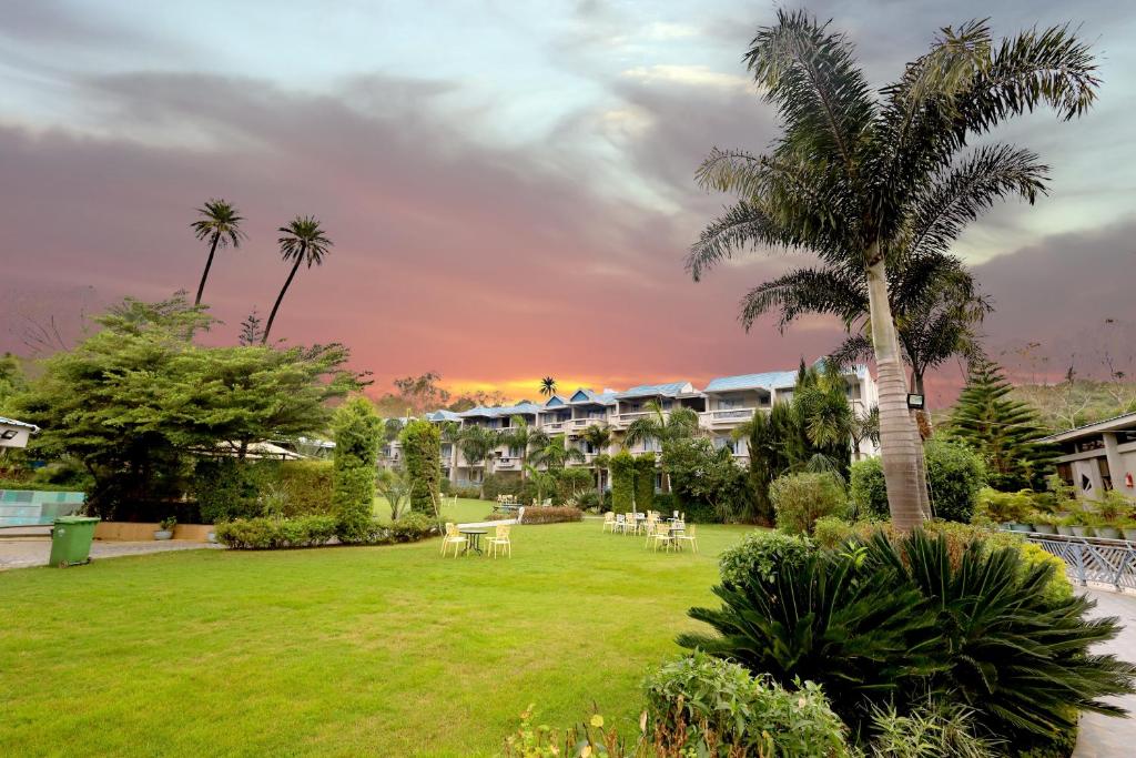 a park with tables and palm trees in a resort at Hummingbird Resort in Mount Ābu