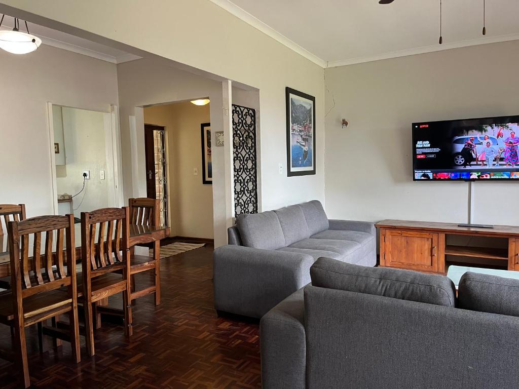 a living room with a couch and a tv on the wall at 10 st Johns - House in Port Shepstone