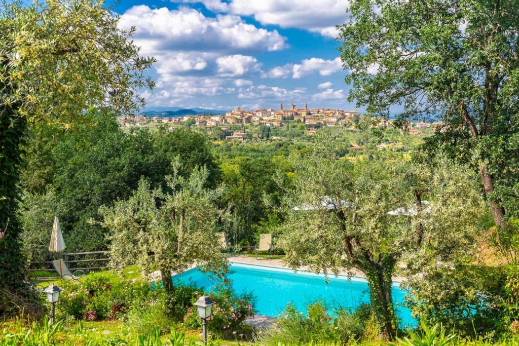 una piscina con alberi e una città sullo sfondo di Il Granaio a Monte San Savino