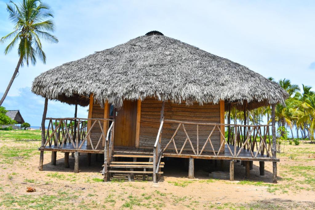 Cabaña pequeña con techo de paja y bancos en Nanano Beach Home Stay en Mtwara