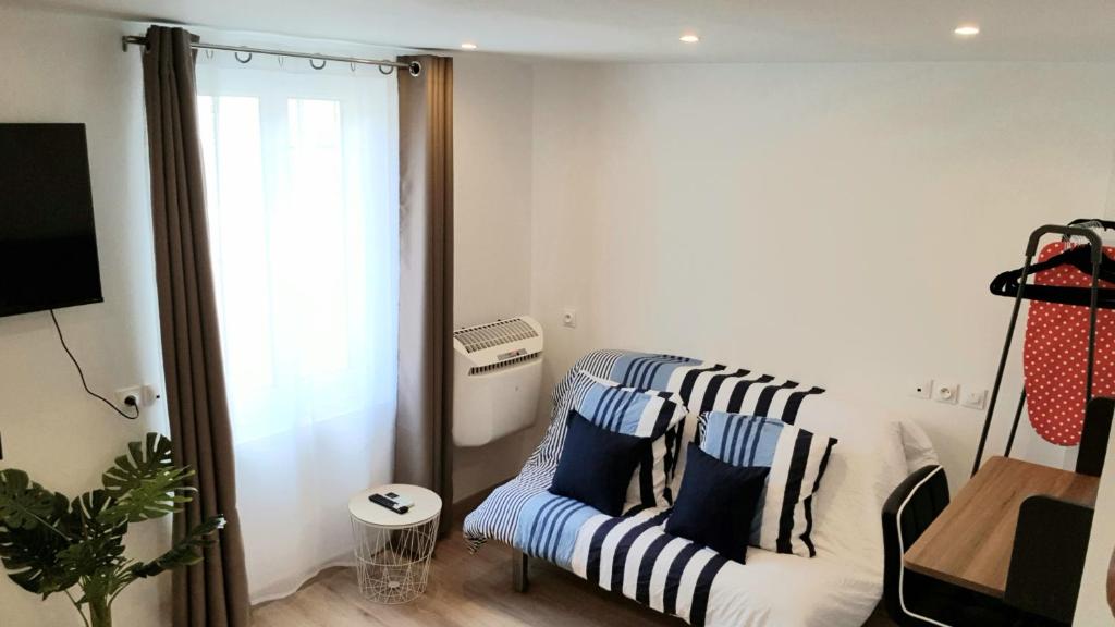 a living room with a couch with blue and white pillows at Escapade Niortaise - Studios climatisés hyper-centre de Niort in Niort