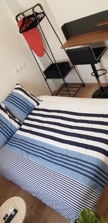a bed with blue and white striped sheets and a desk at Escapade Niortaise - Studios climatisés hyper-centre de Niort in Niort