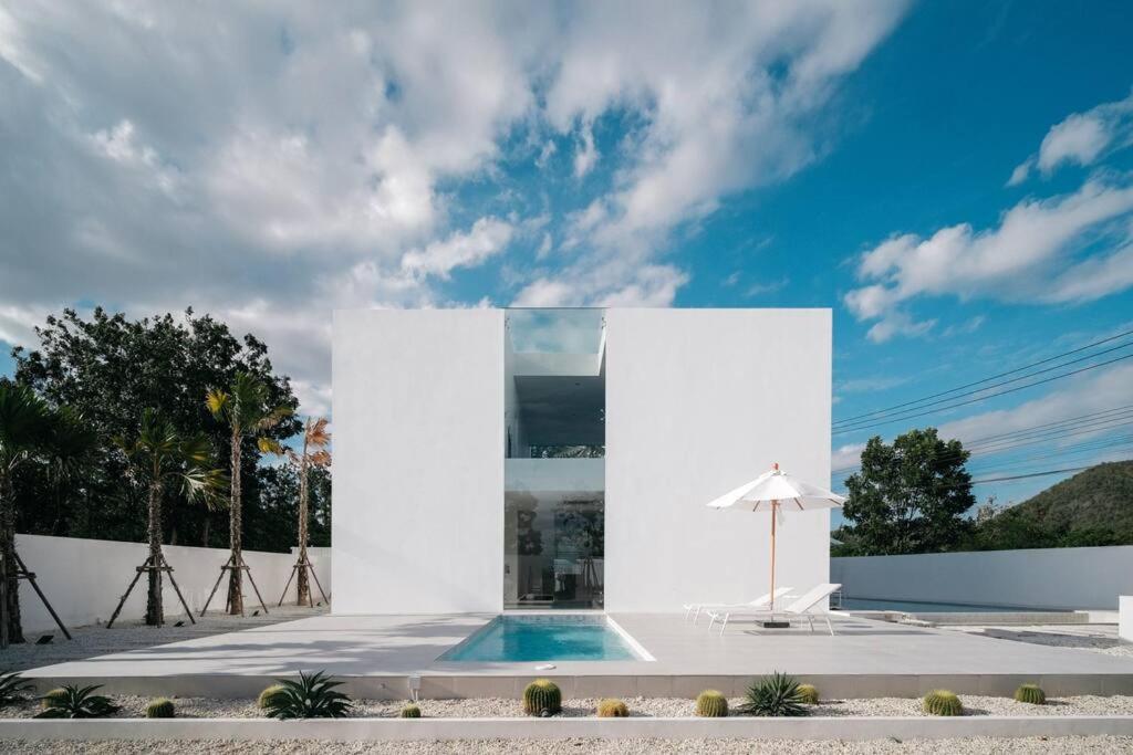 een wit gebouw met een zwembad ervoor bij HER HUAHIN POOL VILLA in Hua Hin