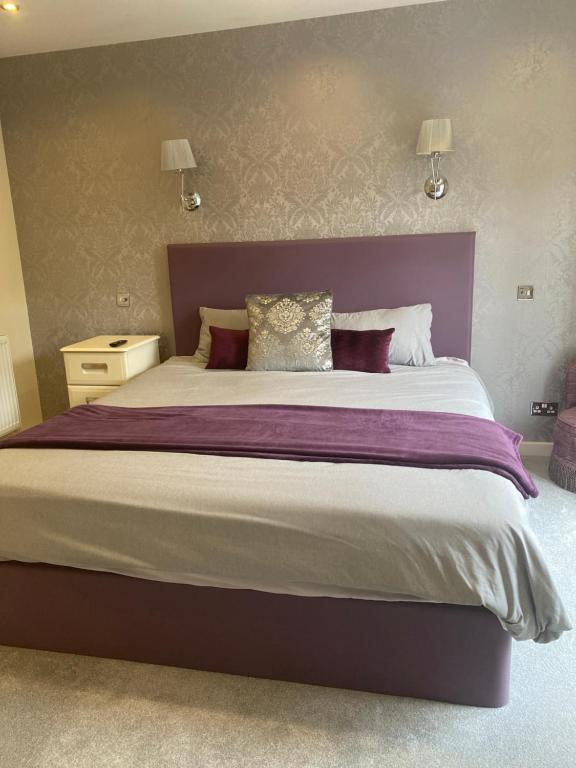 a large bed with a purple headboard in a bedroom at Lamorna in Olney