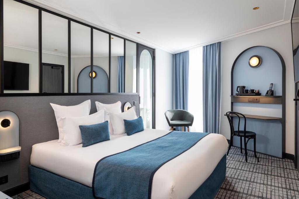 a hotel room with a large bed and a desk at Hôtel de France Gare de Lyon Bastille in Paris