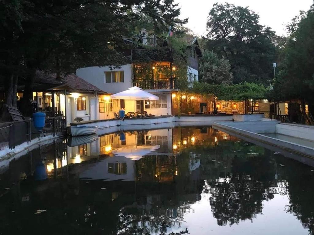 uma casa com piscina à noite em Рибарник Forest Мagic em Topolitsa