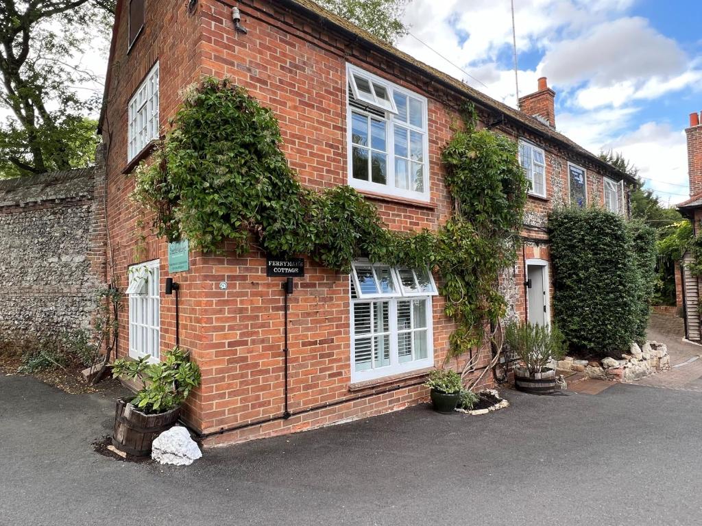 a red brick house with white windows and plants at Ferryman`s Cottage at The Beetle & Wedge in Moulsford