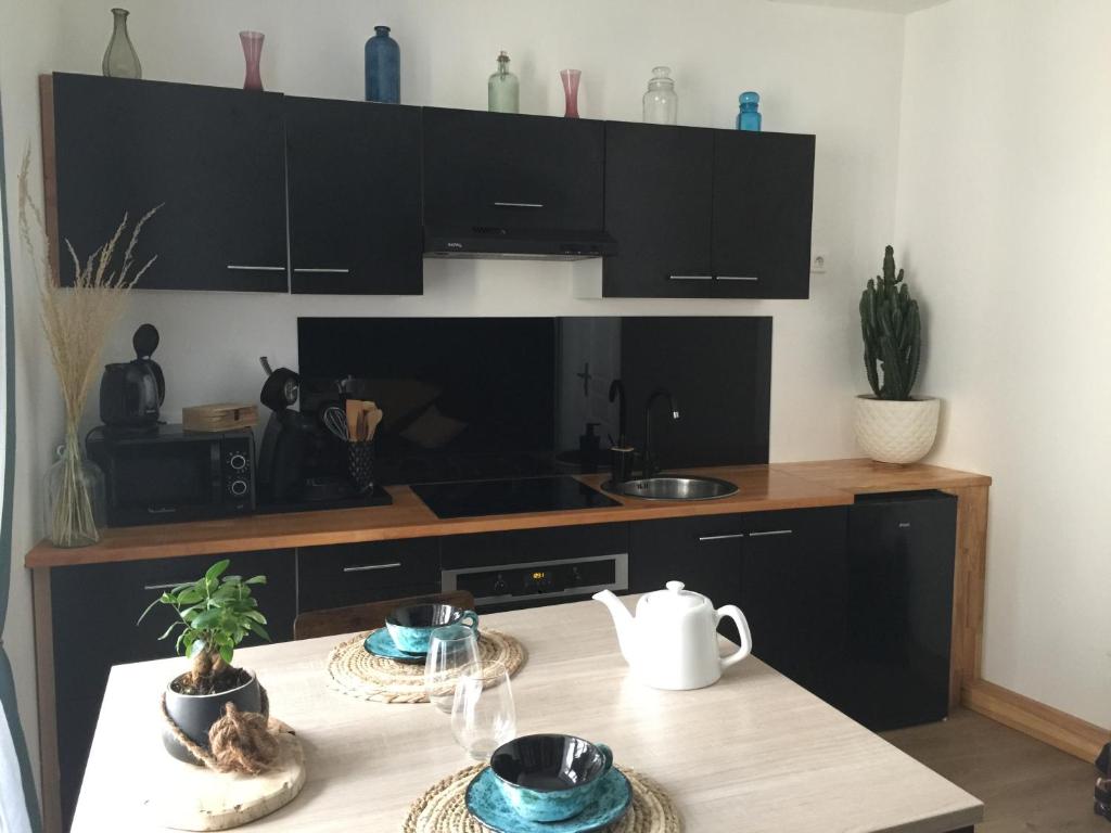 une cuisine avec des armoires noires et une table dans l'établissement Le Nocla, à Aiguilhe