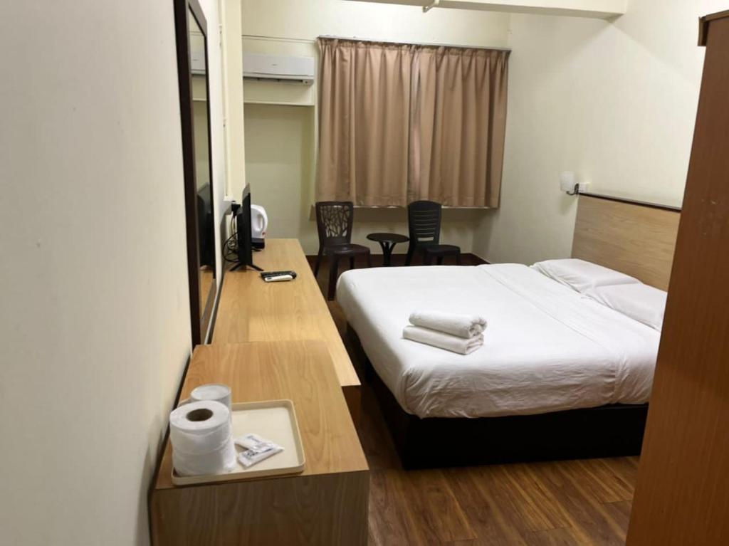 a hotel room with a bed and a desk with a phone at Hotel 75 Temerloh in Temerloh