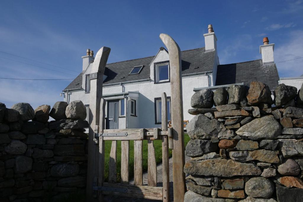 Casa blanca con puerta y pared de piedra en Macleod Cottage - Isle of Lewis Self-Catering en Port of Ness