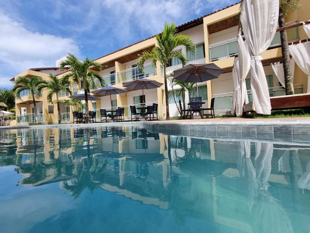 un complejo con una piscina con sillas y sombrillas en Pousada Água Viva, en Porto de Galinhas