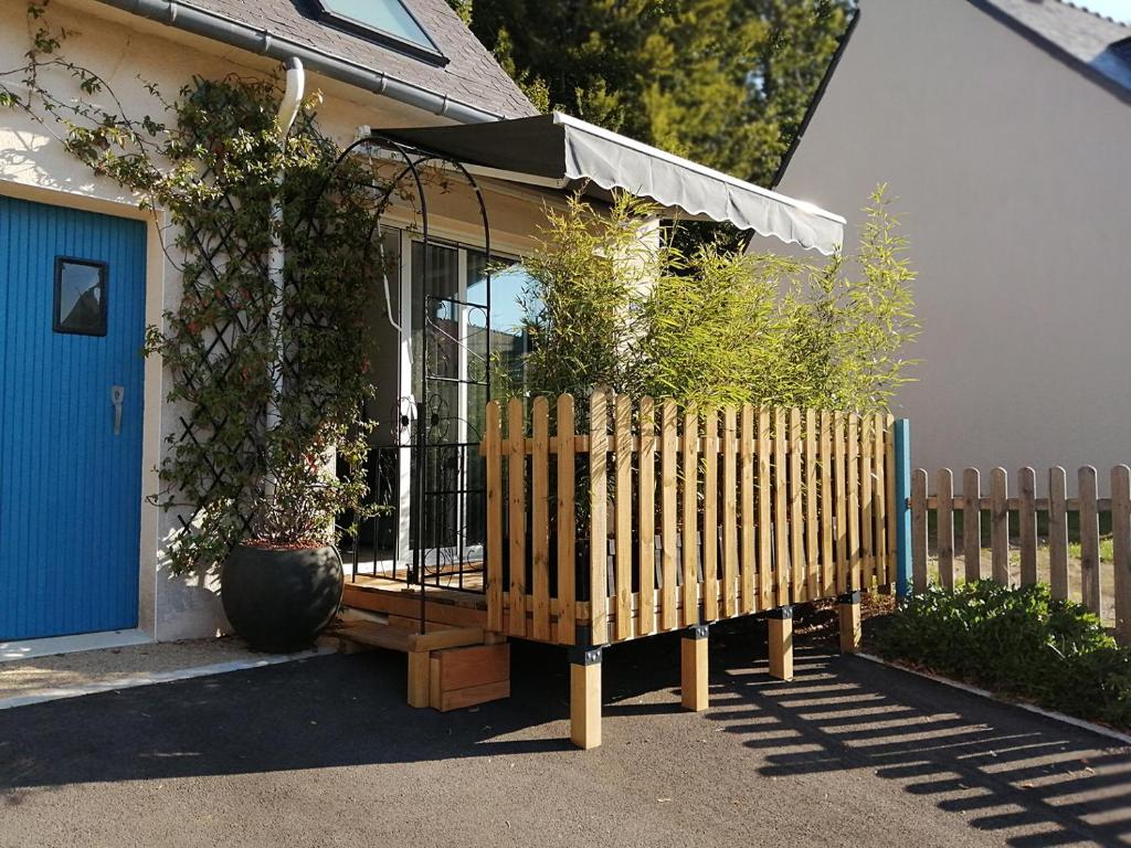 ein Holzzaun vor einem Haus mit einem Regenschirm in der Unterkunft Duplex du Bois d'Amour in Quimper